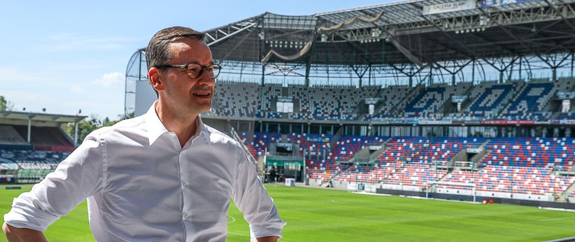 Premier Mateusz Morawiecki na tle stadionu.