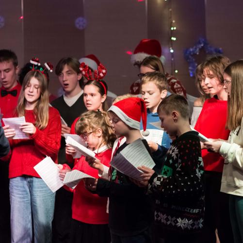 zdjęcie przedstawia część chóru szkolnego na scenie sali koncertowej podczas wykonania utworu, ujęcie z bliska