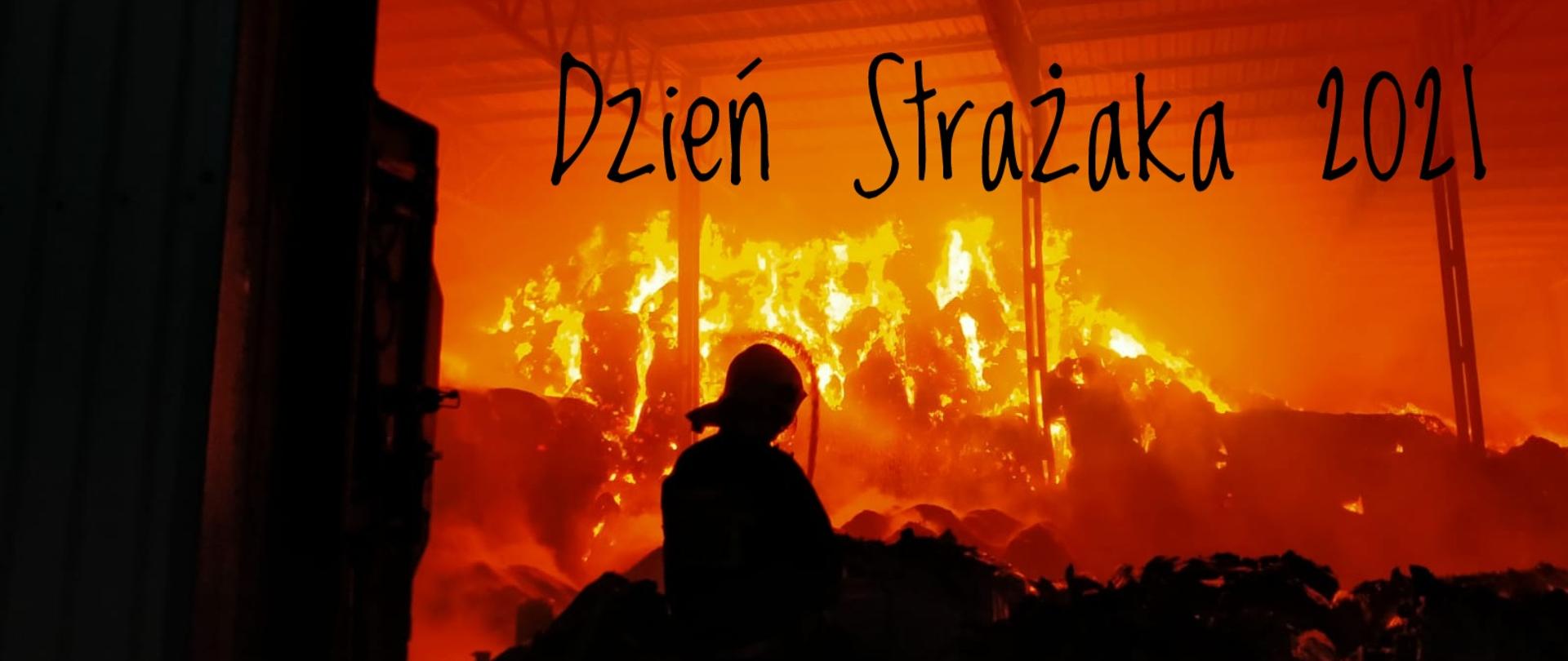 Zdjęcie przedstawia strażaka gaszącego pożar balotów słomy w Przytocznej