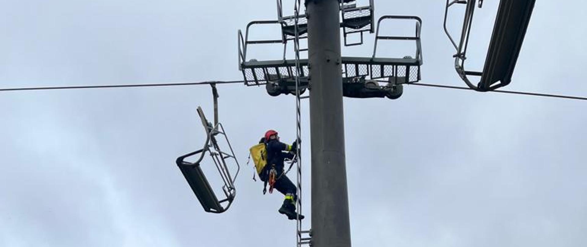 Ratownik wysokościowy podczas wchodzenia po drabinie na kolejkę linową