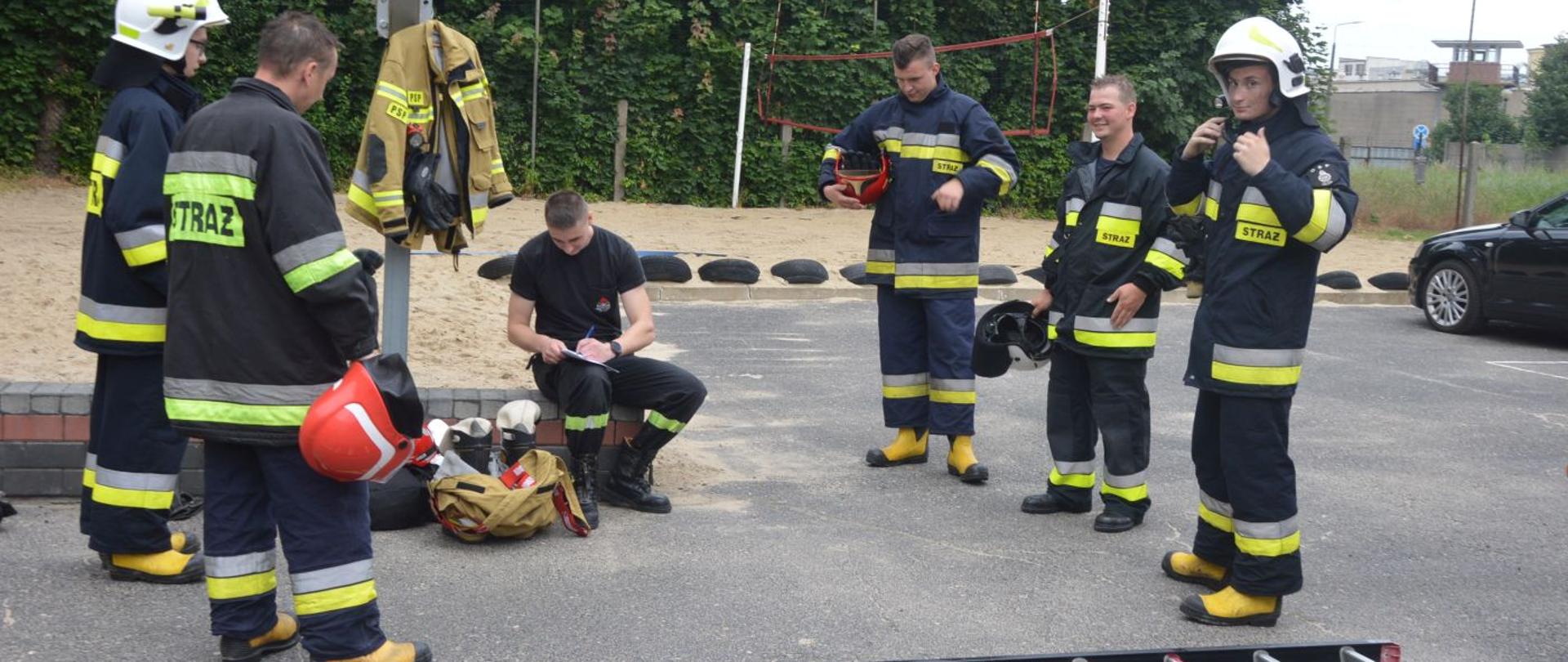 Szkolenie podstawowe - egzamin końcowy. Plac Komendy Powiatowej PSP w Rawiczu. Strażak PSP z członkami OSP zdającymi egzamin końcowy. Stanowisko - drabiny przenośne. 