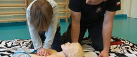 Ćwiczenia z zakresu resuscytacji krążeniowo-oddechowej – uczestnik zajęć wykonuje uciski klatki piersiowej na fantomie pod czujnym okiem strażaka.