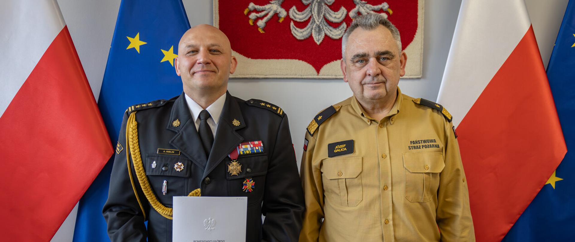Na zdjęciu widoczni na tle orła białego i flag biało czerwonej i unijnej z-ca komendanta głównego nadbryg.Józef Galica z powołanym na stanowisko zastępcy małopolskiego komendanta wojewódzkiego PSP st. bryg. dr inż. Arkadiuszem Kielin.