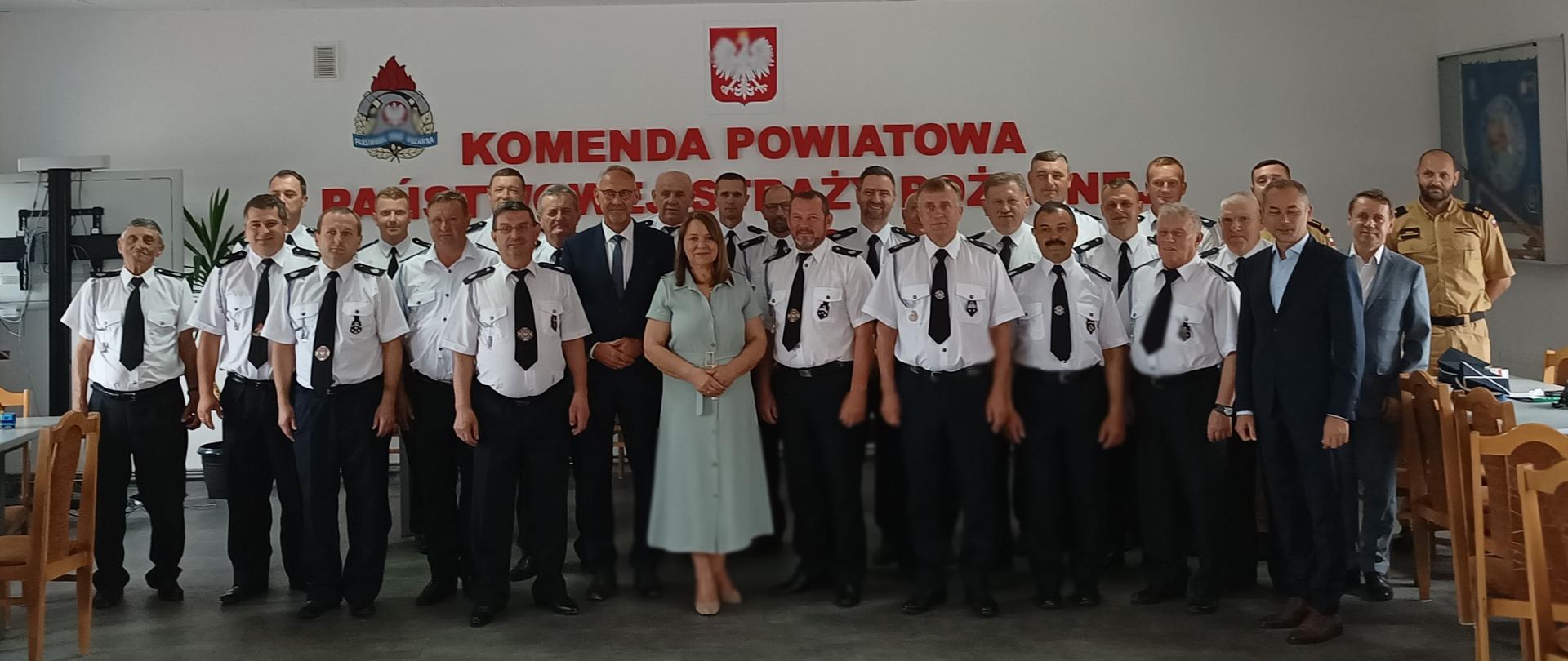 Zdjęcie wykonane podczas spotkanie w trakcie którego doszło do podpisania oraz przekazania umów na zakup sprzętu i wyposażenia dla jednostek Ochotniczych Straży Pożarnych. Na zdjęciu widoczni druhowie prezesi OSP ubrani w białych koszulach oraz zaproszeni goście Pani Teresa Pamuła posłanka na sejm RP, st. bryg. Janusz Jabłoński zastępca podkarpackiego komendanta wojewódzkiego PSP, Pan Adam Skiba Prezes Zarządu Wojewódzkiego Funduszu Ochrony Środowiska i Gospodarki Wodnej w Rzeszowie, Pan Wiesław Kapel wójt gminy Lubaczów, Pan Robert Serkis wójt gminy Horyniec-Zdrój oraz bryg. Michał Lautenszleger komendant powiatowy PSP w Lubaczowie.