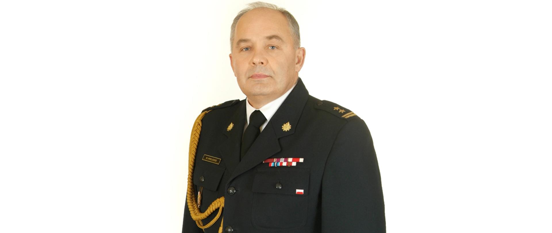Zdjęcie przedstawia komendanta miejskiego państwowej straży pożarnej w Skierniewicach w mundurze wyjściowym na białym tle.
