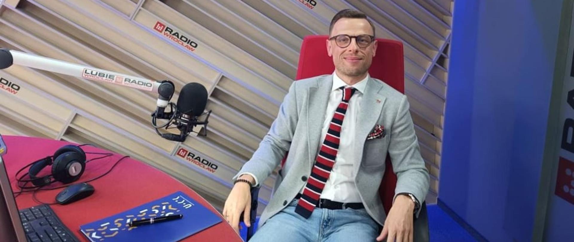 Dolnośląski Wojewódzki Inspektor Inspekcji Handlowej - Pan Tomasz Resler siedzący na czerwonym fotelu w studio radiowym.