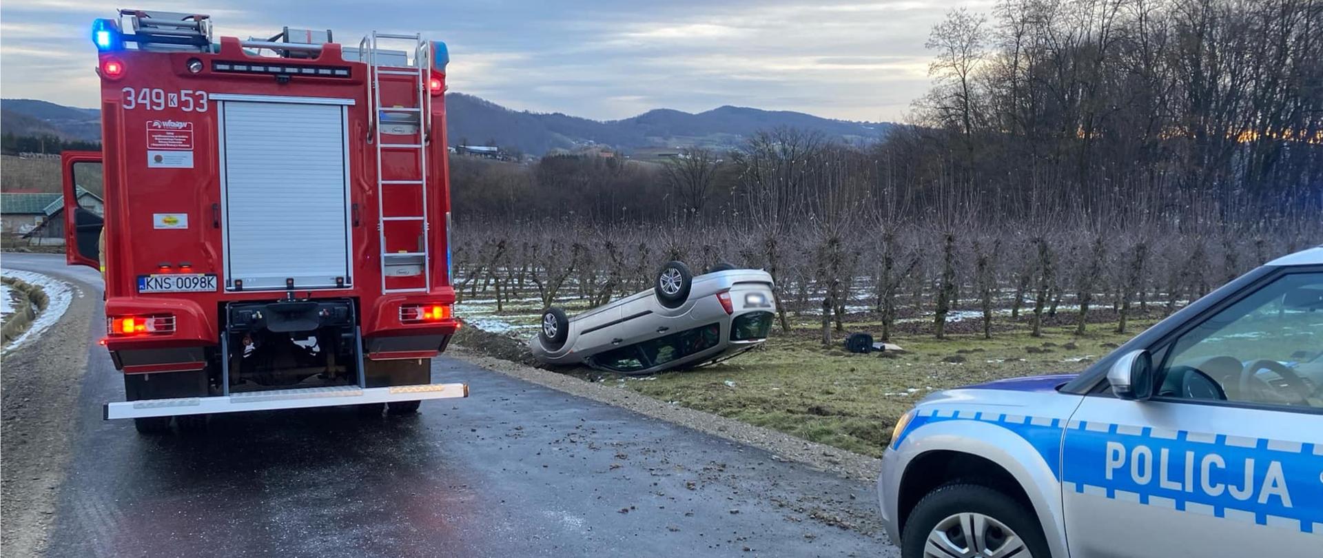 Samochód osobowy na dachu poz drogą oraz samochody służb na drodze