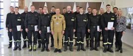 Grupowe zdjęcie uczestników szkolenia (14 strażaków) w towarzystwie Zastępcy Komendanta Centralnej Szkoły PSP, dwóch wykładowców oraz kobiety