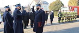 Uroczystości odejścia na emeryturę funkcjonariusza Komendy odbywające się na tle wozów strażackich oraz strażaków