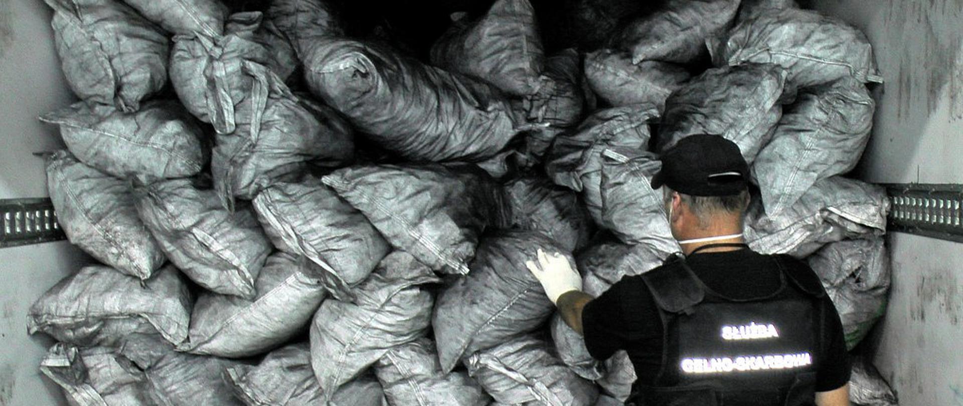 Funkcjonariusz Służby Celno-Skarbowej we wnętrzu naczepy z workami.