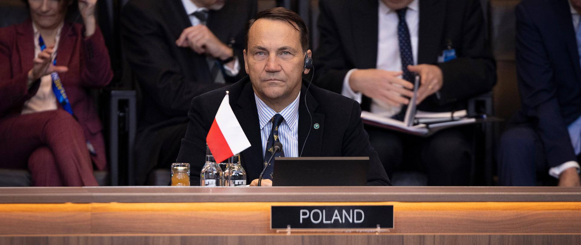 Deputy Prime Minister Radosław Sikorski sitting at the table behind the country name tag