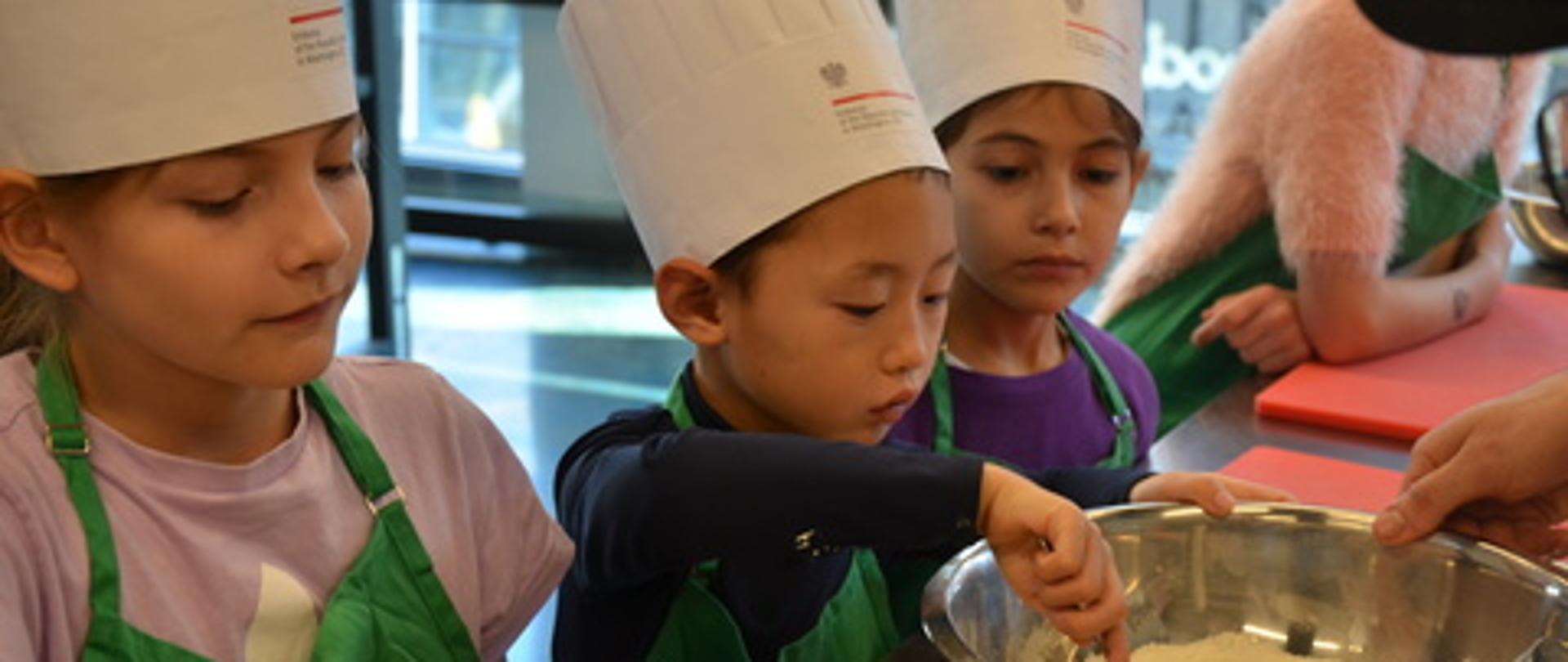 Czwórka małych dzieci przygotowuje ciasto w dużej misce