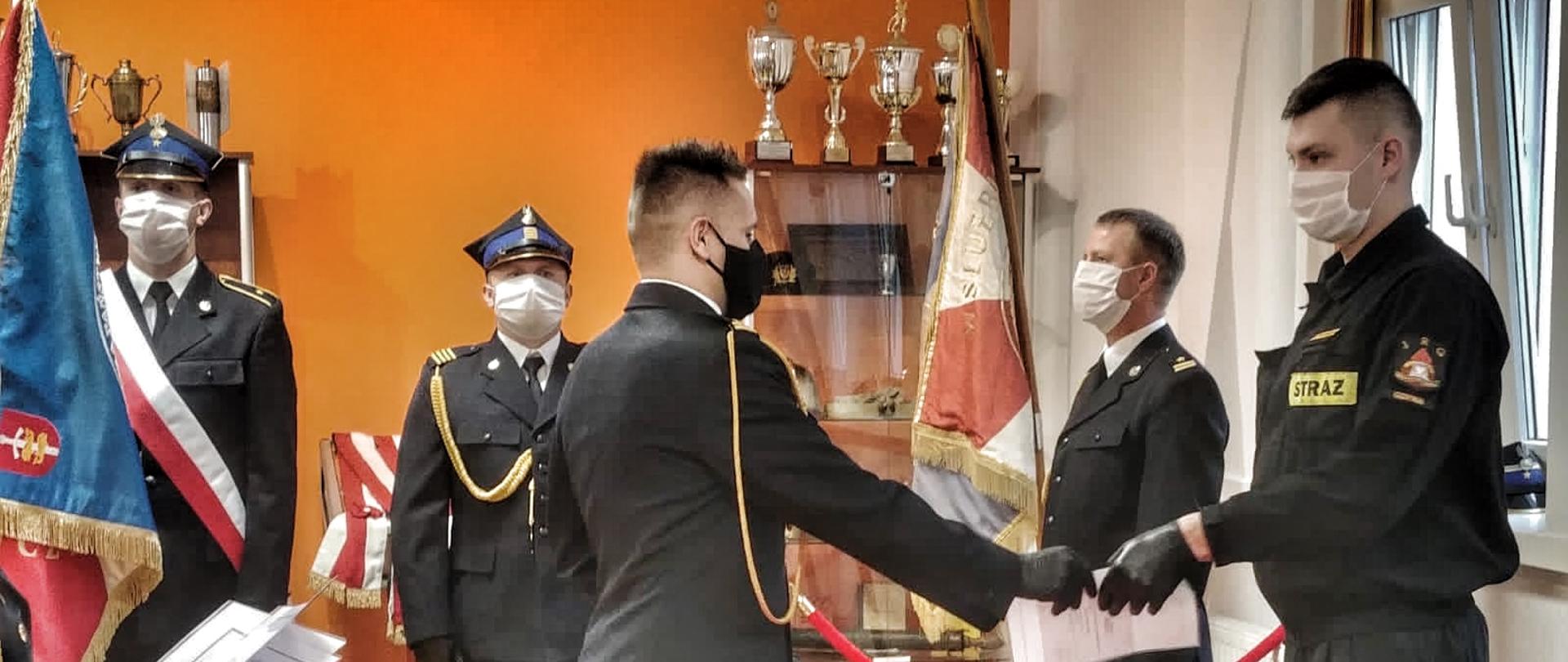 Komendant Miejski PSP w Gdyni wręcza awans funkcjonariuszowi PSP. W tle stoi Poczet Sztandarowy.