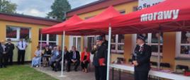 Zastępca pomorskiego komendanta wojewódzkiego Państwowej Straży Pożarnej przemawia trzymając mikrofon podczas uroczystości.