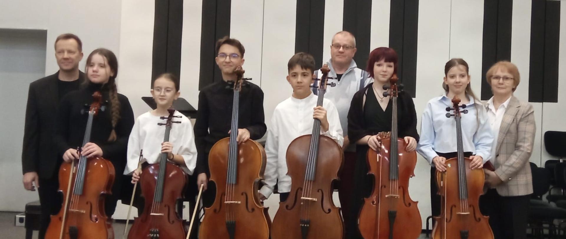 Wszyscy wykonawcy razem z nauczycielami stoją na scenie.