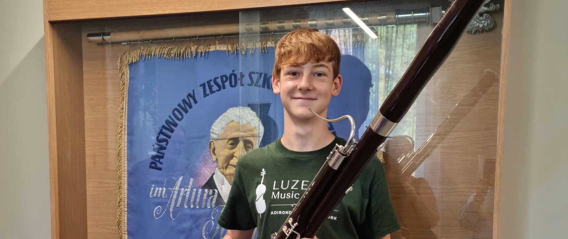 na zdjęciu na tle sztandaru szkoły, fagocista uczeń naszej szkoły Błażej Beszczyński