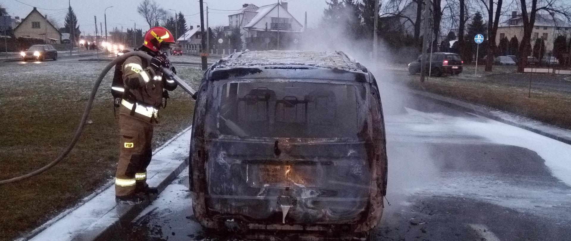 Strażak podczas gaszenia samochodu. Auto całkowicie spalone.
