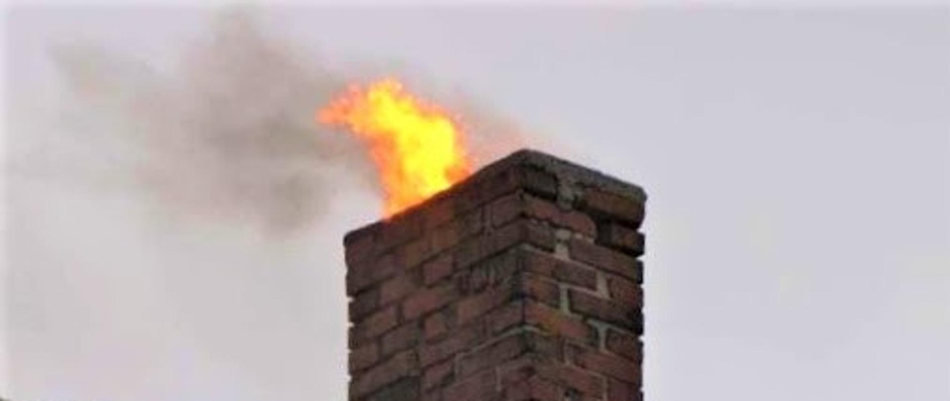 Na zdjęciu widoczny komin z którego wydobywa się ogień.