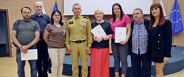Pamiątkowe zdjęcie siedmiu osób będących uczestnikami szkolenia z zakresu ochrony ludności i obrony cywilnej dla kadry w urzędach obsługujących organy ochrony ludności w towarzystwie Zastępcy Komendanta Centralnej Szkoły PSP