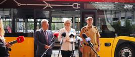 Na zdjęciu uczestnicy konferencji prasowej na tle autobusu ZTM przed nimi mikrofony różnych redakcji.