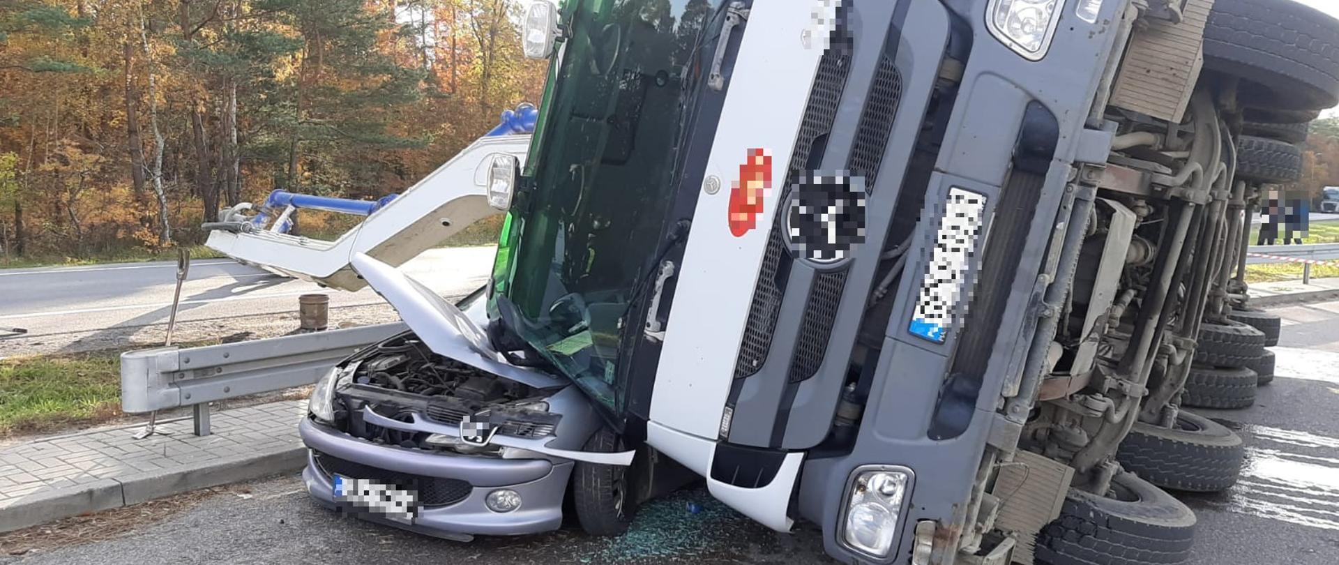 Na zdjęciu widoczne wywrócenie się samochodu ciężarowego (gruszki) na samochód osobowy. Wysięgnik pompy gruszki blokuje drogę krajową DK nr 6.