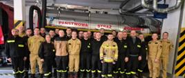 Strażacy stoją w szyku na garażu , w tle cysterna samochodowa z napisem Państwowa Straż Pożarna