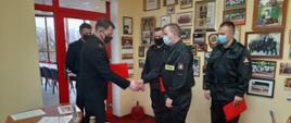Na zdjęciu widać trzech strażaków oraz dwóch komendantów którzy mianują na wyższe stanowiska służbowe 