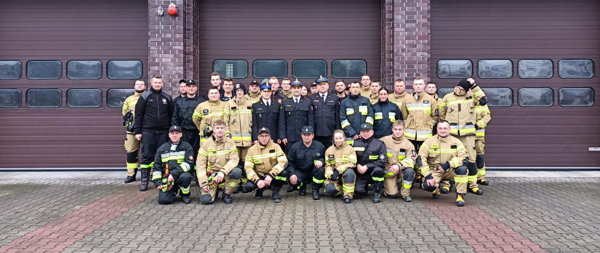 Strażacy OSP z komisją egzaminacyjną przed budynkiem komendy (zdjęcie grupowe).