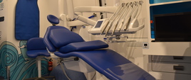 Białe wnętrze dentobusu, na pierwszym planie widać granatowy fotel stomatologiczny, a dookoła niego znajdują się wszelkiego rodzaju narzędzia i przybory.