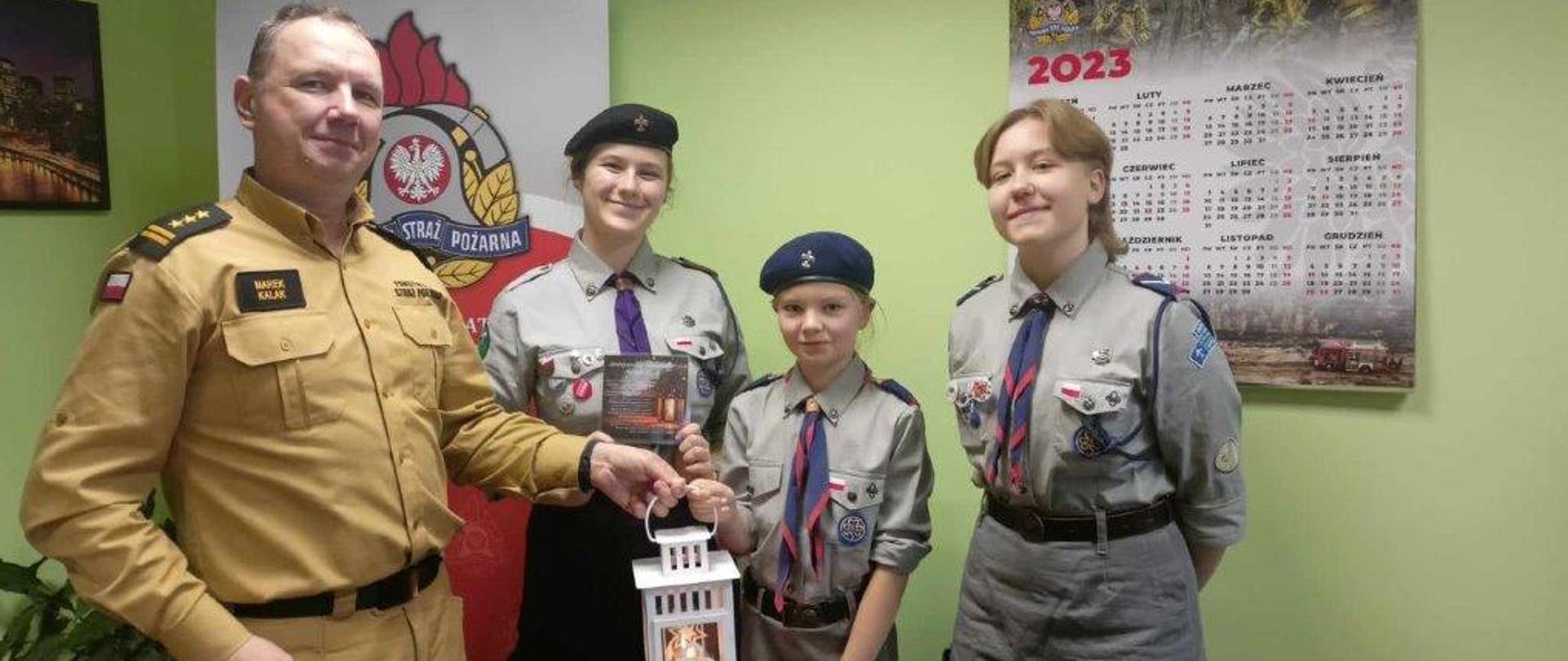 Zdjęcie ukazuje harcerzy przekazujących lampion ze światełkiem pokoju komendantowi powiatowemu