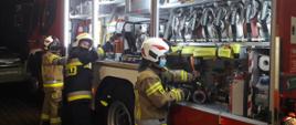 Trzy uczestniczki szkolenia wyjmują sprzęt z samochodu pożarniczego.