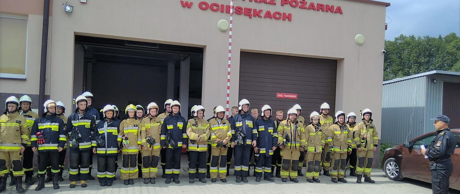 Zdjęcie przedstawia wszystkich uczestników szkolenia podstawowego dla druhów OSP na tle remizy w Ociesękach.