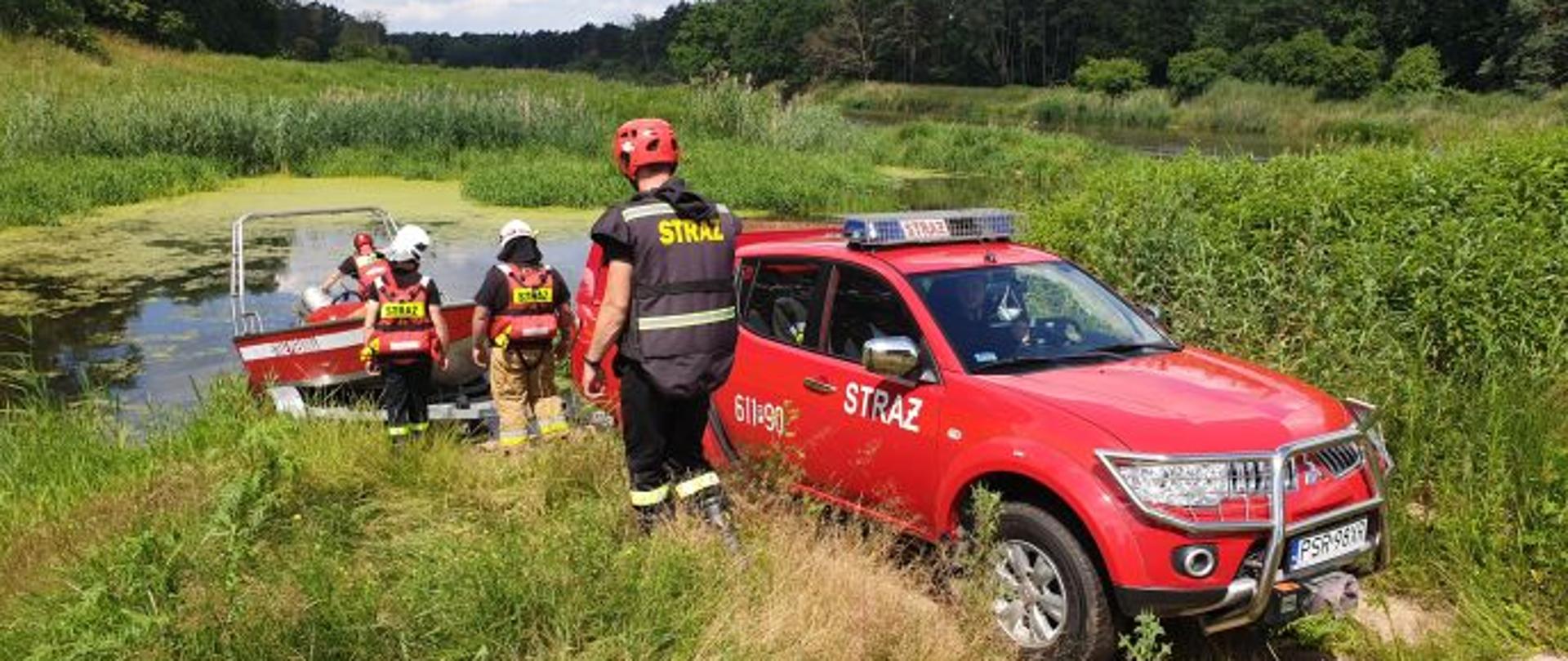 Strażacy wodują łódź ratowniczą na rzece