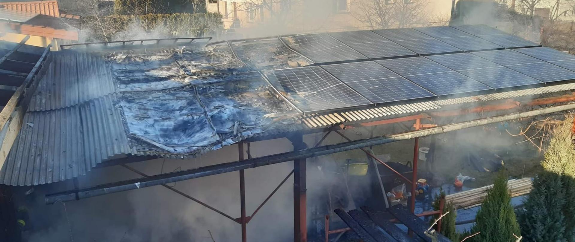 Widok ugaszonej zniszczonej wiaty z panelami fotowoltaicznymi