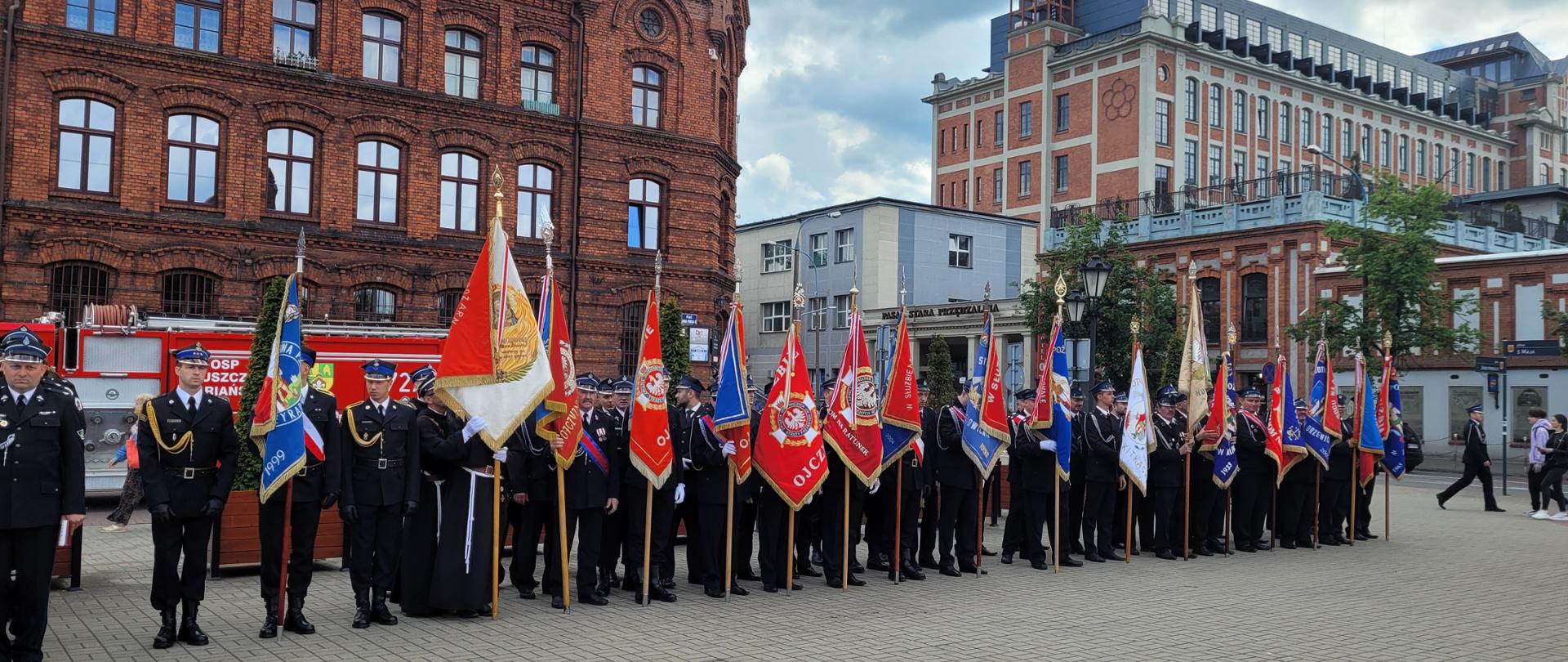 Poczty sztandarowe stoją w rzędzie na placu Jana Pawła II
