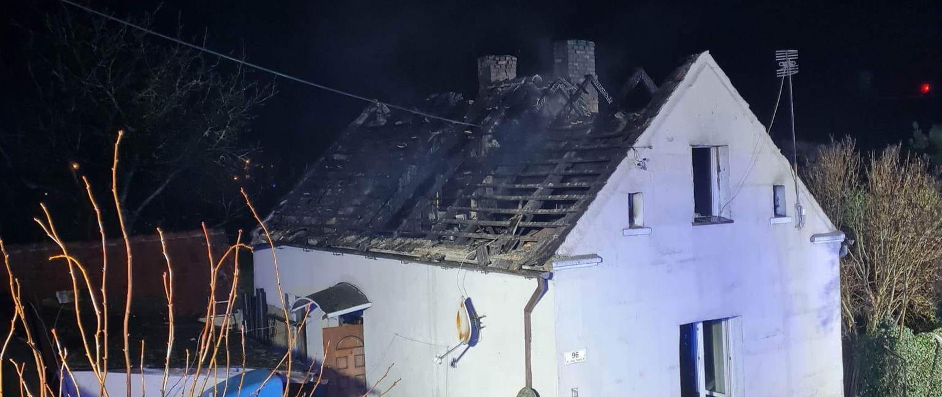 Widać uszkodzony dach budynku mieszkalnego, jest noc