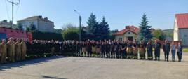 Zdjęcie grupowe uczestników ćwiczeń na podsumowaniu przed budynkiem OSP. 