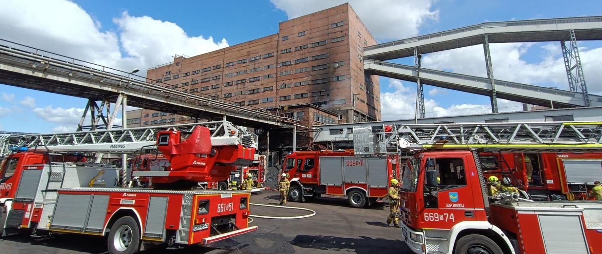 Samochody gaśnicze na tle budynku kopalni objętego pożarem