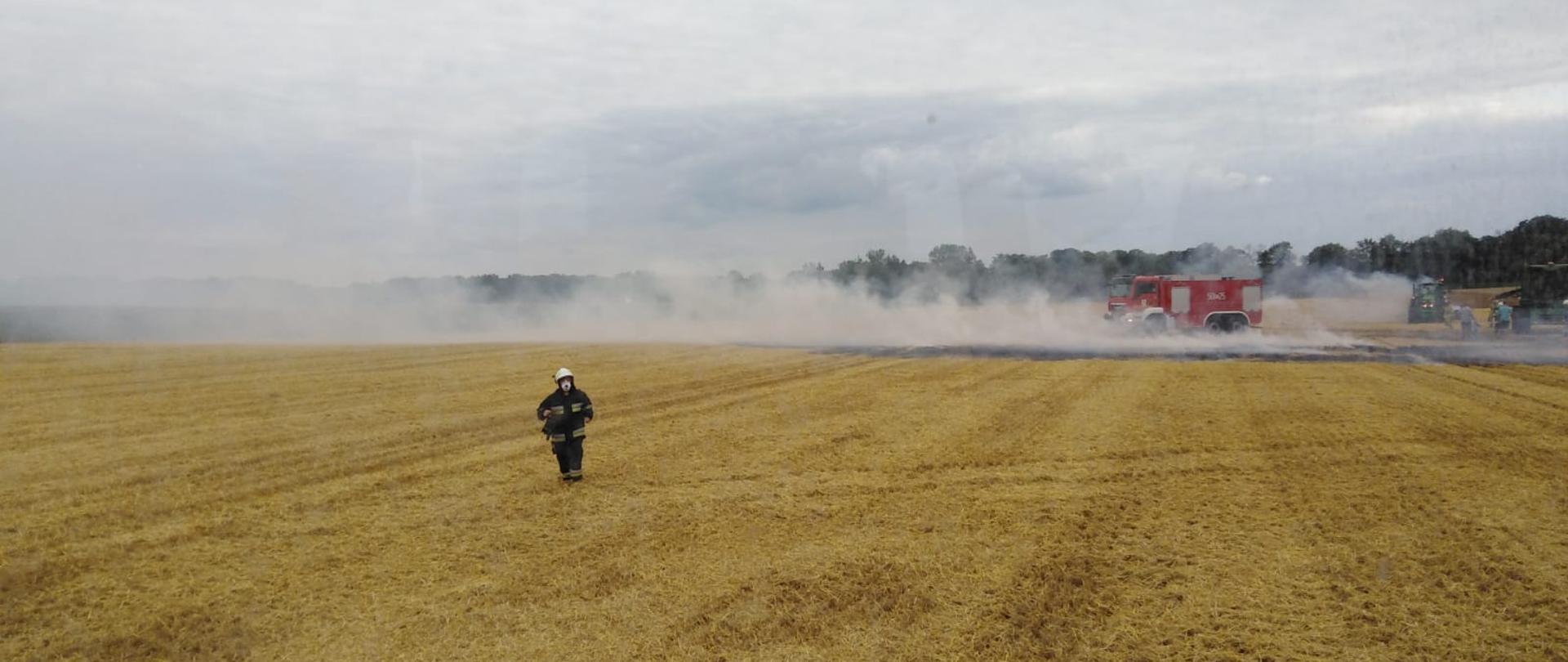 Zdjęcie przedstawia pożar ścierniska na polu podczas prac w trakcie żniw