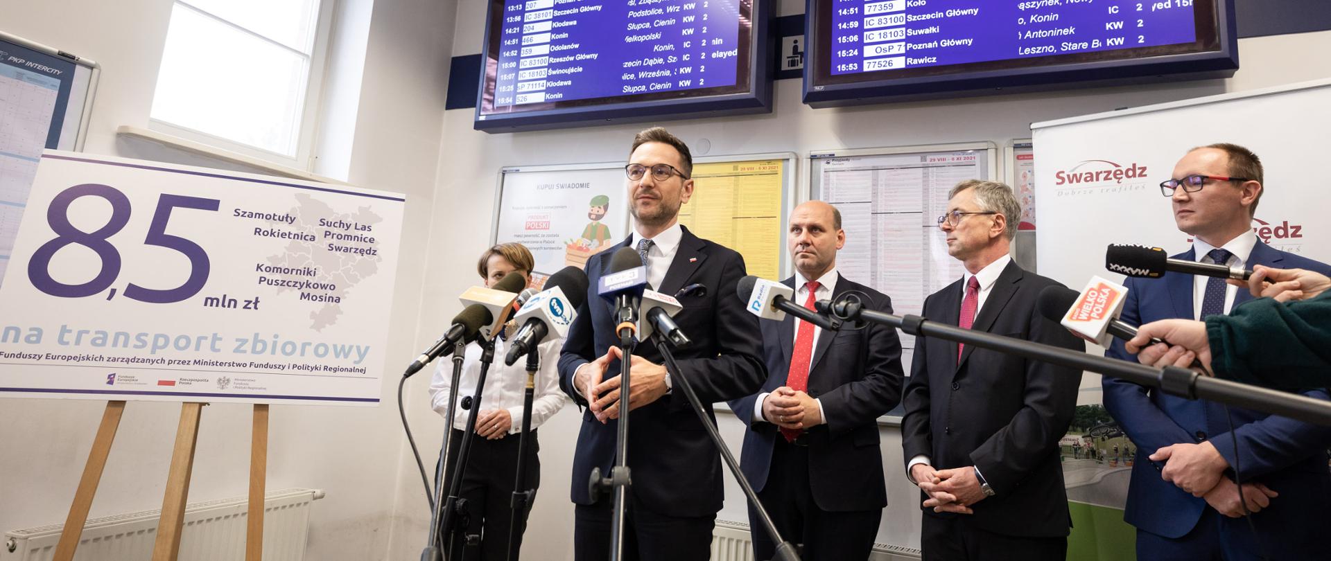 Minister Buda, minister Szynkowski i poseł Emilewicz stoją na dworcu PKP i mówią do mikrofonów mediów