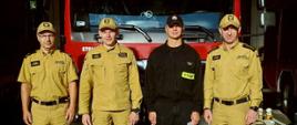 4 strażaków, w tym komendant i jego zastępca stoją przed wozem strażackim i pozują do zdjęcia. Jeden z nich rozpoczyna służbę w JRG w Gostyniu oraz jeden został mianowany naczelnikiem.