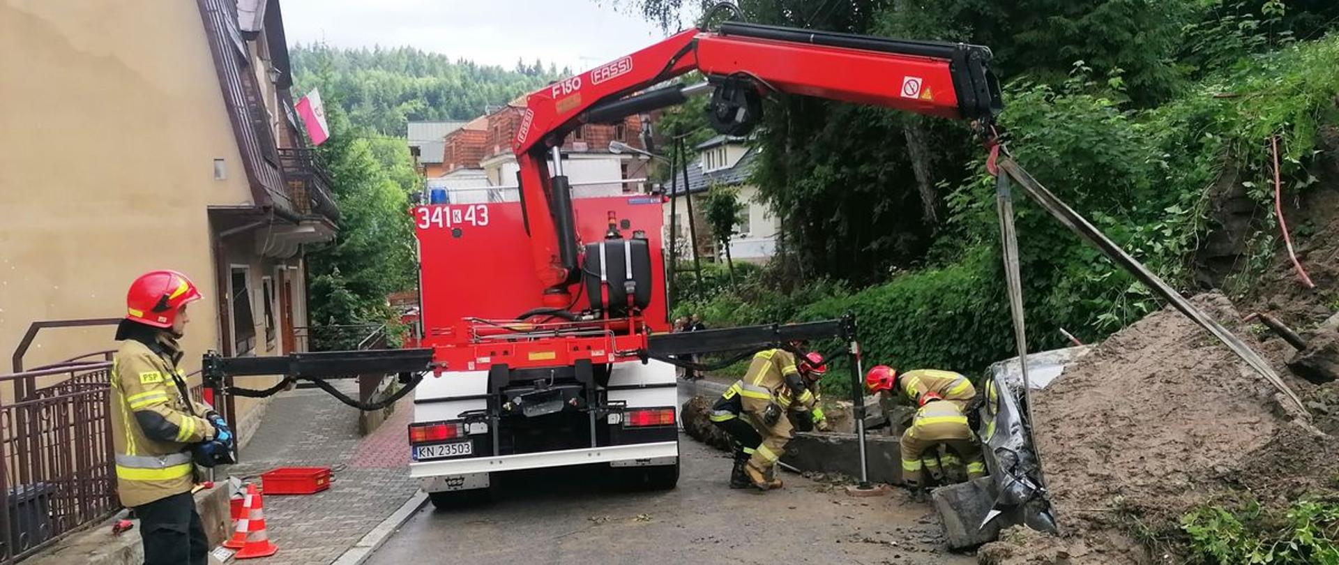 Samochód Ratownictwa Technicznego z JRG nr 1 Nowy Sącz przenosi kawałki muru oporowego.
