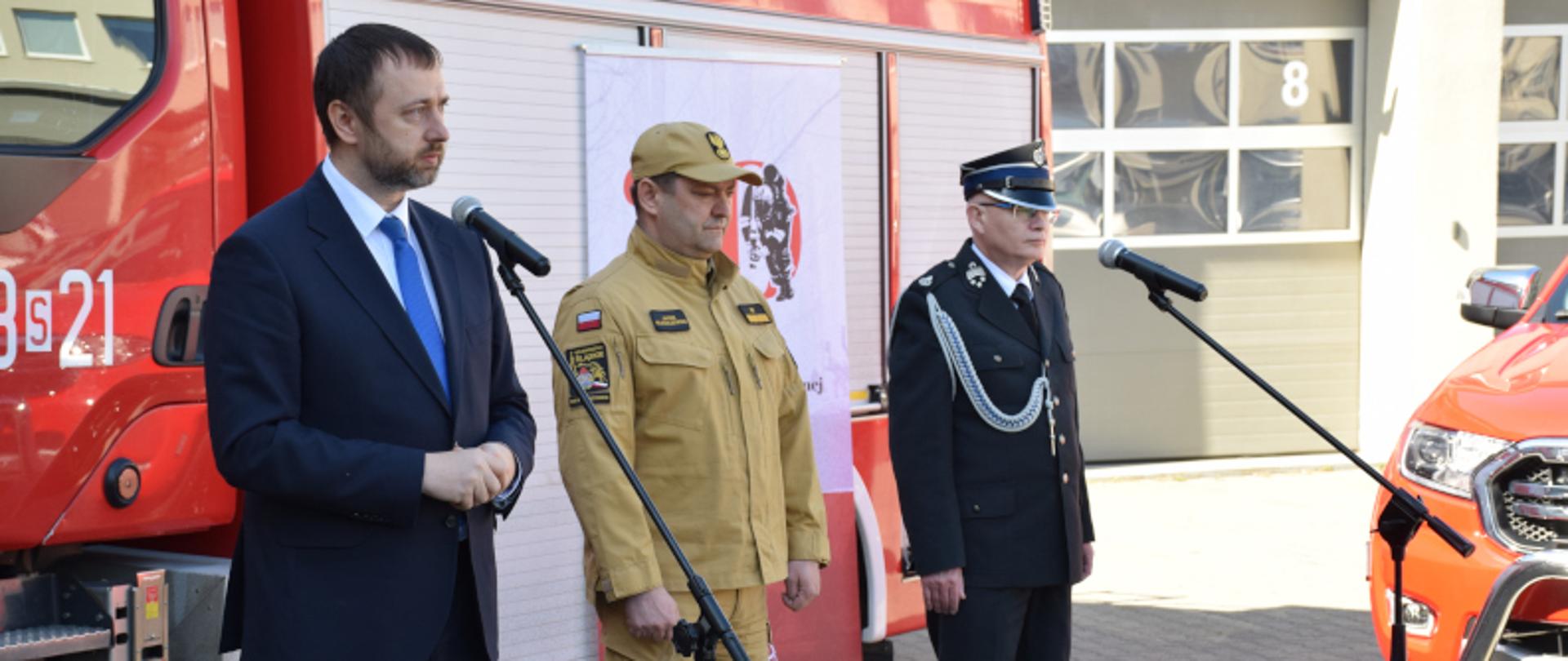 Na tle samochodu ratowniczo-gaśniczego Tomasz Bednarek - Prezes Zarządu Wojewódzkiego Inspektoratu Ochrony Środowiska w Katowicach, Śląski Komendant Wojewódzki PSP nadbryg. Jacek Kleszczewski, Poseł na Sejm RP Waldemar Andzel