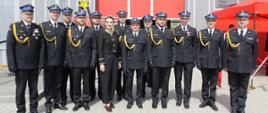 Strażacy w mundurach galowych pozują do zdjęcia z wojewodą pomorską