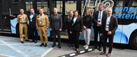 Osoby pozujące do wspólnego zdjęcia na tle autobusu zasilanego wodorem