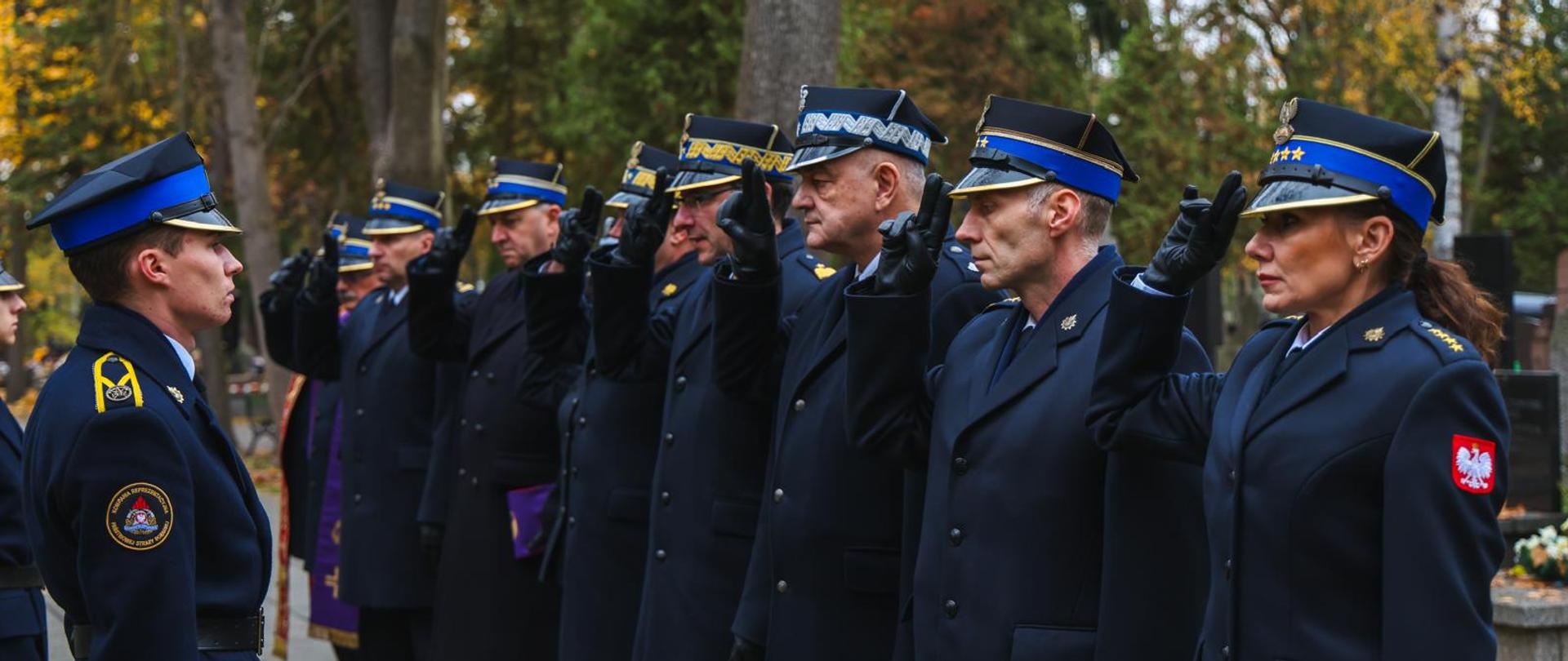 Grupa funkcjonariuszy salutująca nad grobem