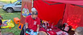 Na zdjęciu widoczny jest Ratownik Polskiego Czerwonego Krzyża poczas pokazywania zawartości AED oraz jak poprawnie go użyć w sytauacji zagrożenia czyjegoś życia.