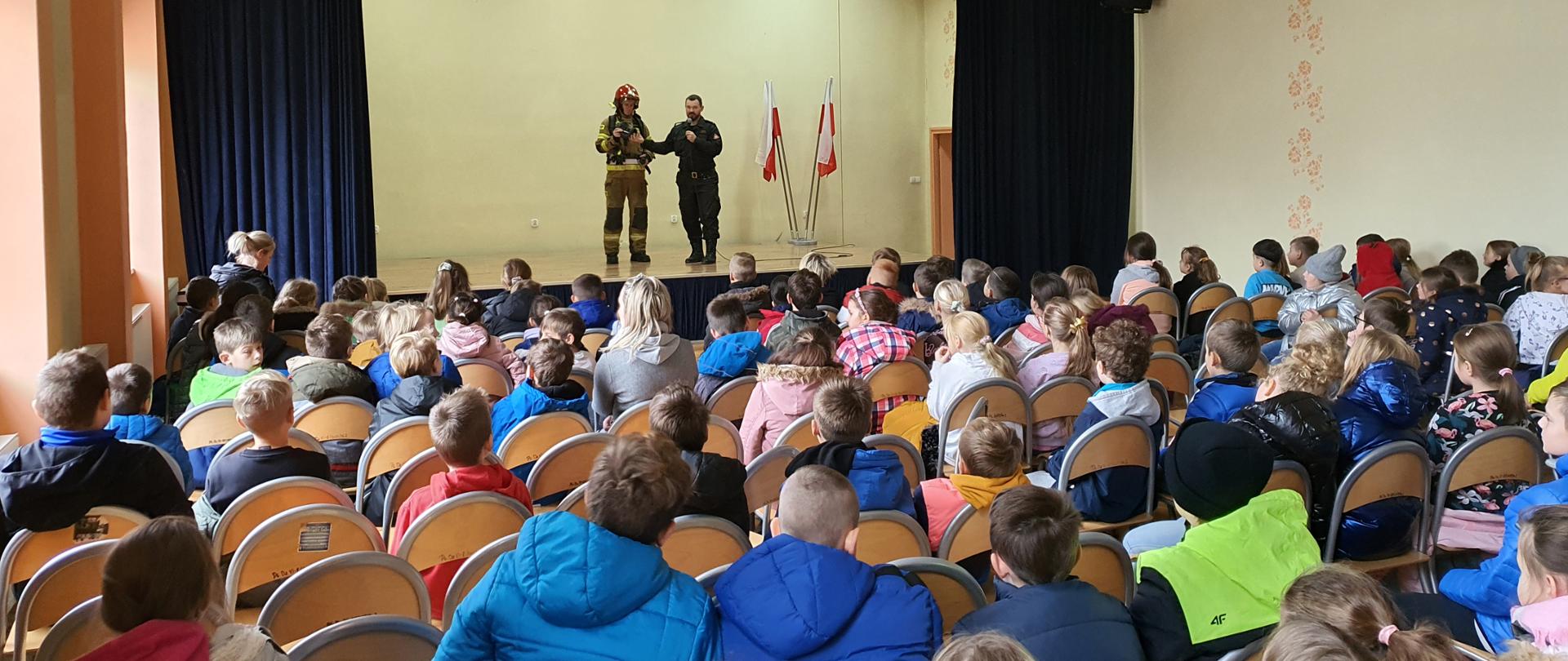 Zdjęcie przedstawia sale na której zgromadzone dzieci słuchały pogadanki strażaków dot. bezpieczeństwa pożarowego