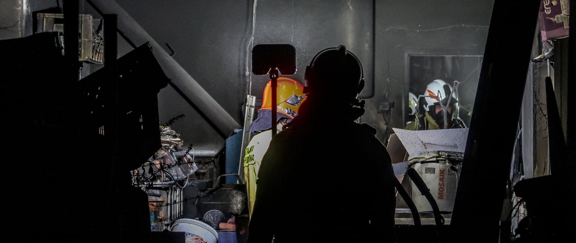 POMIESZCZENIE PO POŻARZE, NA PIERWSZYM PLANIE STRAŻAK