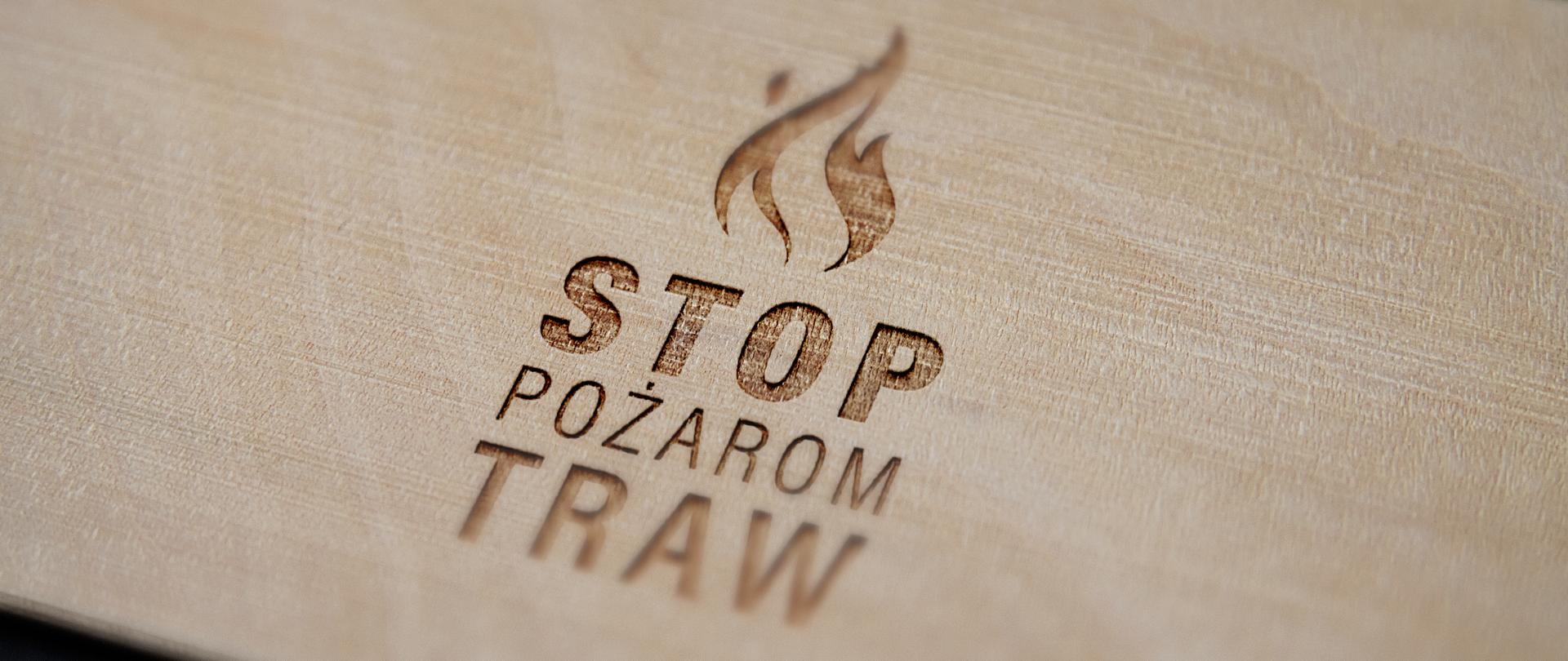 Napis stop pożarom traw wypalony na desce